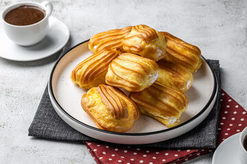 French eclair with custard. Profiteroles with cream on a white plate. Side view. Homemade pastries...