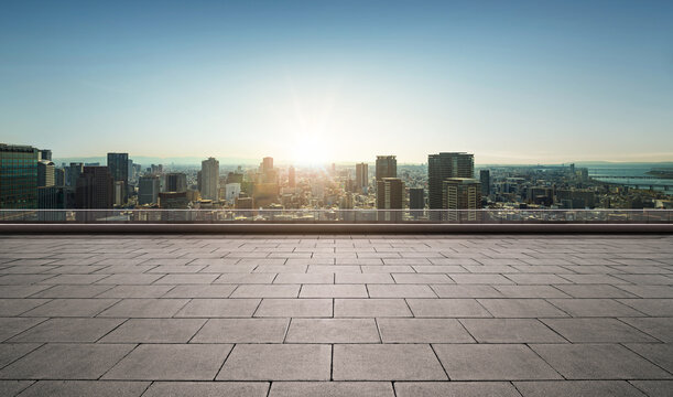 Rooftop empty brick floor with panoramic city skyline during sunrise.