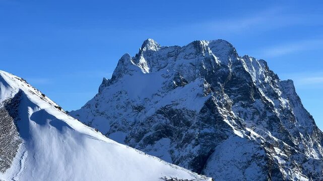 View of Dombay glaciers and mountain peaks in the winter sun. Panorama of the snow-capped Caucasus Mountains in sunny weather. Dombay-Ulgen and Moussa-Achitara mountains. Ski resort in Russia.