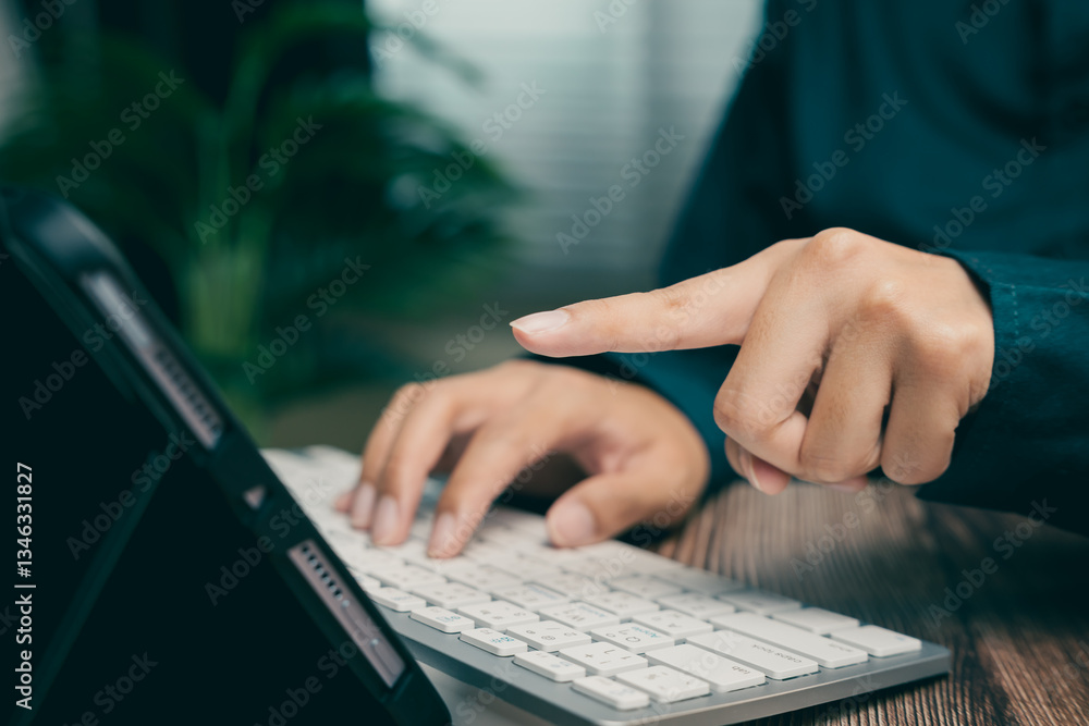 Poster person typing on keyboard while pointing at touchscreen device in modern workspace setting, business