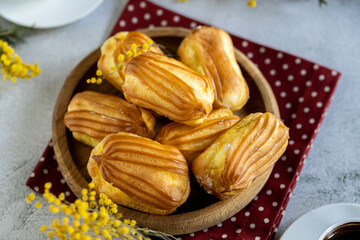 French eclair with custard. Profiteroles with cream on a wooden plate. Eclairs tow view. Flatlay....