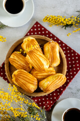 French eclair with custard. Profiteroles with cream on a wooden plate. Eclairs tow view. Flatlay. Natural lighting. Homemade pastries with cream.