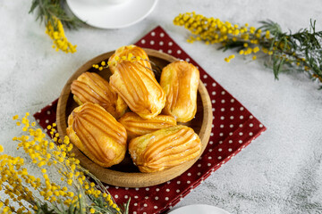 French eclair with custard. Profiteroles with cream on a wooden plate. Eclairs tow view. Flatlay. Natural lighting. Homemade pastries with cream.
