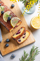Lemon pie with sugar glaze, blueberries, decorated with rosemary and citrus slices on a wooden board