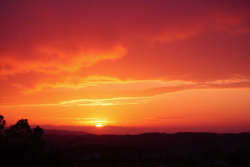 Fototapeta premium the sun is setting over a field with trees in the foreground