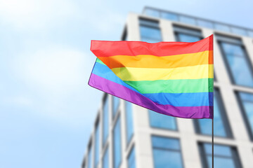 LGBT flag fluttering against building outdoors, low angle view