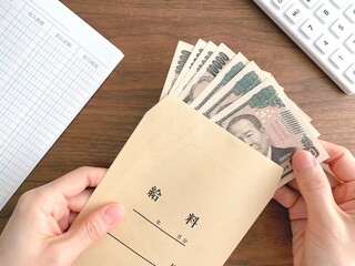 Naklejka premium 机上で給料袋から紙幣を取り出す女性の手元