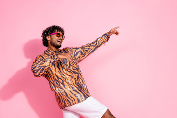 Young stylish man in a tiger-print shirt and sunglasses posing against a vibrant pink background