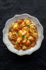 Mac and cheese, the classic pasta with macaroni and Cheddar cheese, baked in the oven, overhead flat lay shot on a black slate background