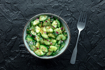 Smashed cucumber salad with red onion, healthy vegan food, green snack, overhead flat lay shot on black