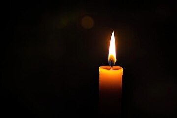 Single candle flame in the dark