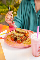 Female enjoying french toast kunafa style served with milk shakes at a fancy cafe restaurant.  