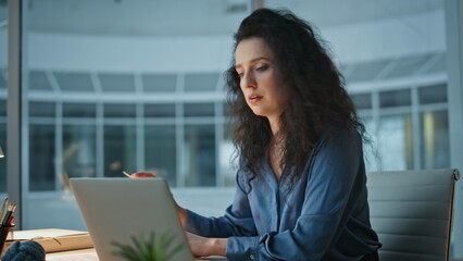 Fototapeta premium Tired executive finishing work in evening office. Overwhelmed woman heachache
