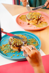 Girl friends eating dubai chocolate kunafa pancakes served at a fancy restaurant cafe.