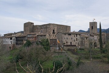 Santa Pau, Spain - Feb 24, 2025: Santa Pau castle. Walking in Santa Pau suburb. Streets, buildings. Lifestyle in the urban area. Cloudy winter day. Selective focus