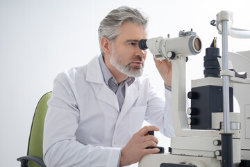 Portrait picture of a male doctor looking into microscope and looking focused