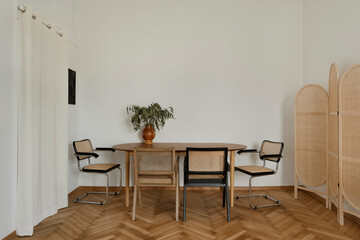 Elegant dining area with woven rattan chairs, a wooden table, and a neutral color palette. A fusion...