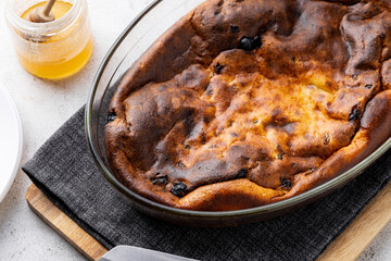 Cottage cheese casserole with raisins in a glass baking dish just out of the oven. Top view. Flatlay. Casserole with honey and berry jam.