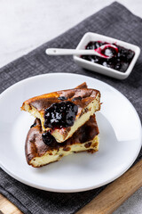 Cottage cheese casserole with berry jam on a white plate. Homemade casserole with cottage cheese and raisins.