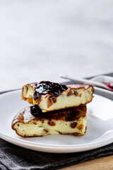 Cottage cheese casserole with berry jam on a white plate. Homemade casserole with cottage cheese and raisins.
