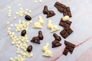 Dark and white chocolate Easter eggs and bunnies with fruit-colored candies and chocolate bars on a counter