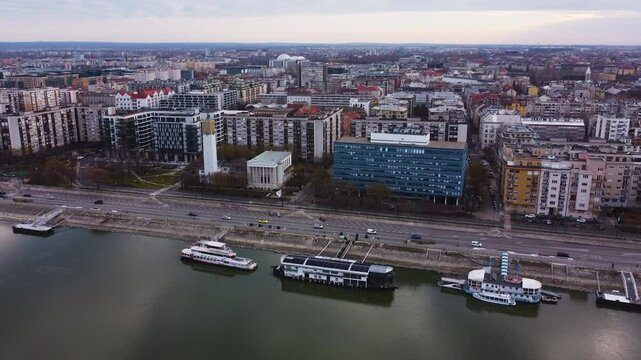 Aerial establishing ascends Reformed church in Budapest spanning Danube River, city buildings in background with ferries in water