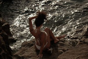 curly young fit female model pose on the rocky beach at Spain Andalucia