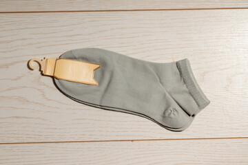 A pair of gray ankle socks with a blank beige tag attached, placed on a wooden surface.