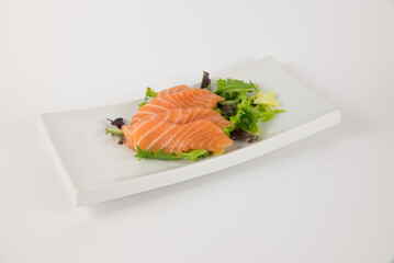 Fresh salmon sashimi on lettuce served on a white plate
