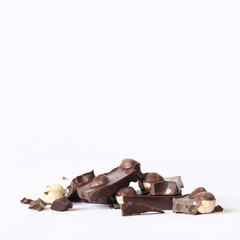Chocolate with whole hazelnuts. Pieces of dark chocolate with hazelnuts. Dessert. Pieces of dark chocolate with nuts on a white background. Food concept, sweets
