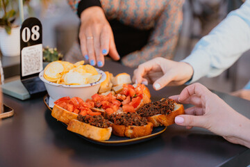 Hands Reaching for Bruschetta and Chips at Outdoor Table