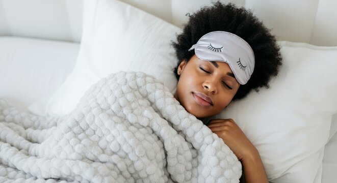 Peaceful young woman sleeping with eye mask on white bed