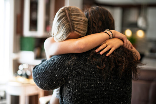 Compassionate mother comforting depressed sad teen girl, hugging daughter with love
