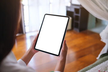 Mockup image of a woman holding tablet with blank desktop white screen on the bed at home