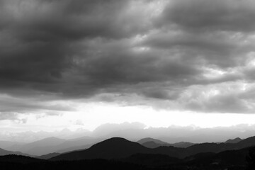 Obraz premium Landscape of the mountain range with cloudy sky in black and white shot