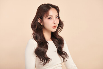 Fototapeta premium A beautiful young Asian woman with clean, fresh skin against a beige background. Skincare, facial treatment, cosmetology, beauty, and spa. An elegant portrait of an Asian woman.