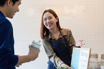 Sustainability and Customer Engagement. A barista encourages customers to bring their own cups for...