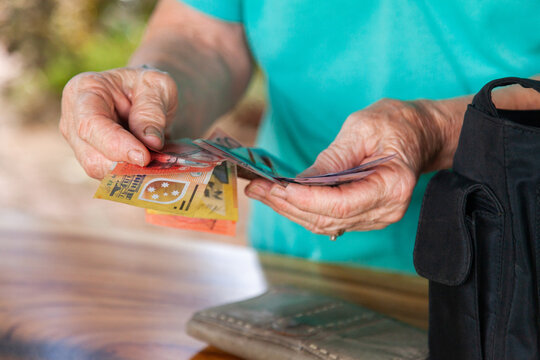 Old persons hands handing over australian bank notes