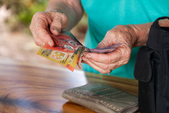 Hands of old person holding australian bank notes