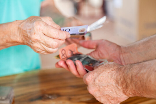 Hands of old person handing over money to a middle aged man