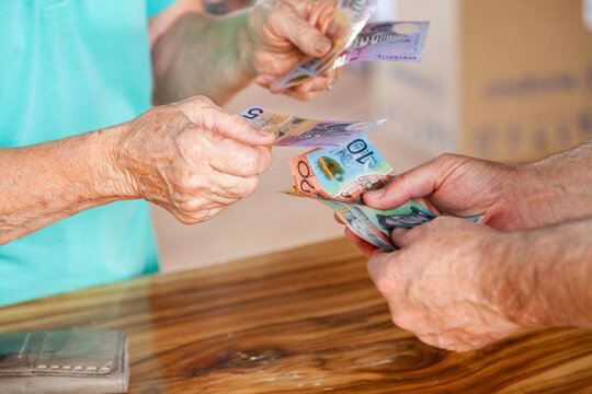 Hands of old person handing over money to a middle aged man