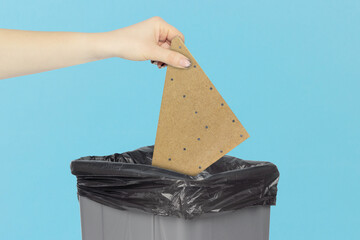 throw wooden triangle in trash can, wooden triangle in hand in front of trash can