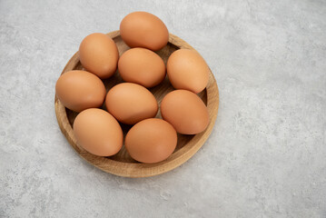 Chicken eggs lie on a wooden plate. Fresh egg for morning breakfast. Concept of agricultural products and natural food