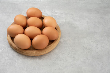 Chicken eggs lie on a wooden plate. Fresh egg for morning breakfast. Concept of agricultural products and natural food