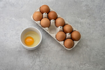 Chicken eggs lie in a box, one of them is broken. Fresh eggs for morning breakfast. Concept of...