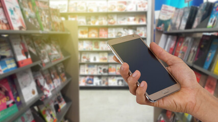 smartphone hold in hand with blurred bookstore.