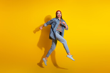 Cheerful young woman wearing colorful casual clothes jumps joyfully against a vibrant yellow background