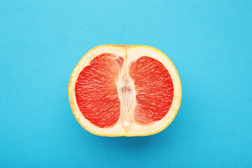 Grapefruit minimal abstract concept. Half a juicy grapefruit close up on blue background.