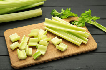 Fresh green cut celery on cutting board on black wooden background