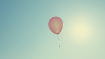 Obraz premium Single pink balloon floating in a clear blue sky.